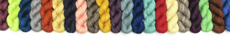 A large pile of several dozen skeins of yarn with every color of the rainbow.